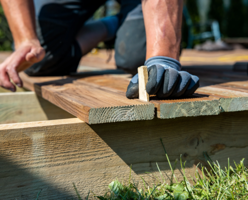 A contractor building a wooden deck in a backyard with natural wood materials