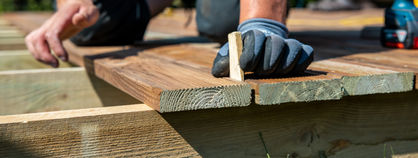 A contractor building a wooden deck in a backyard with natural wood materials