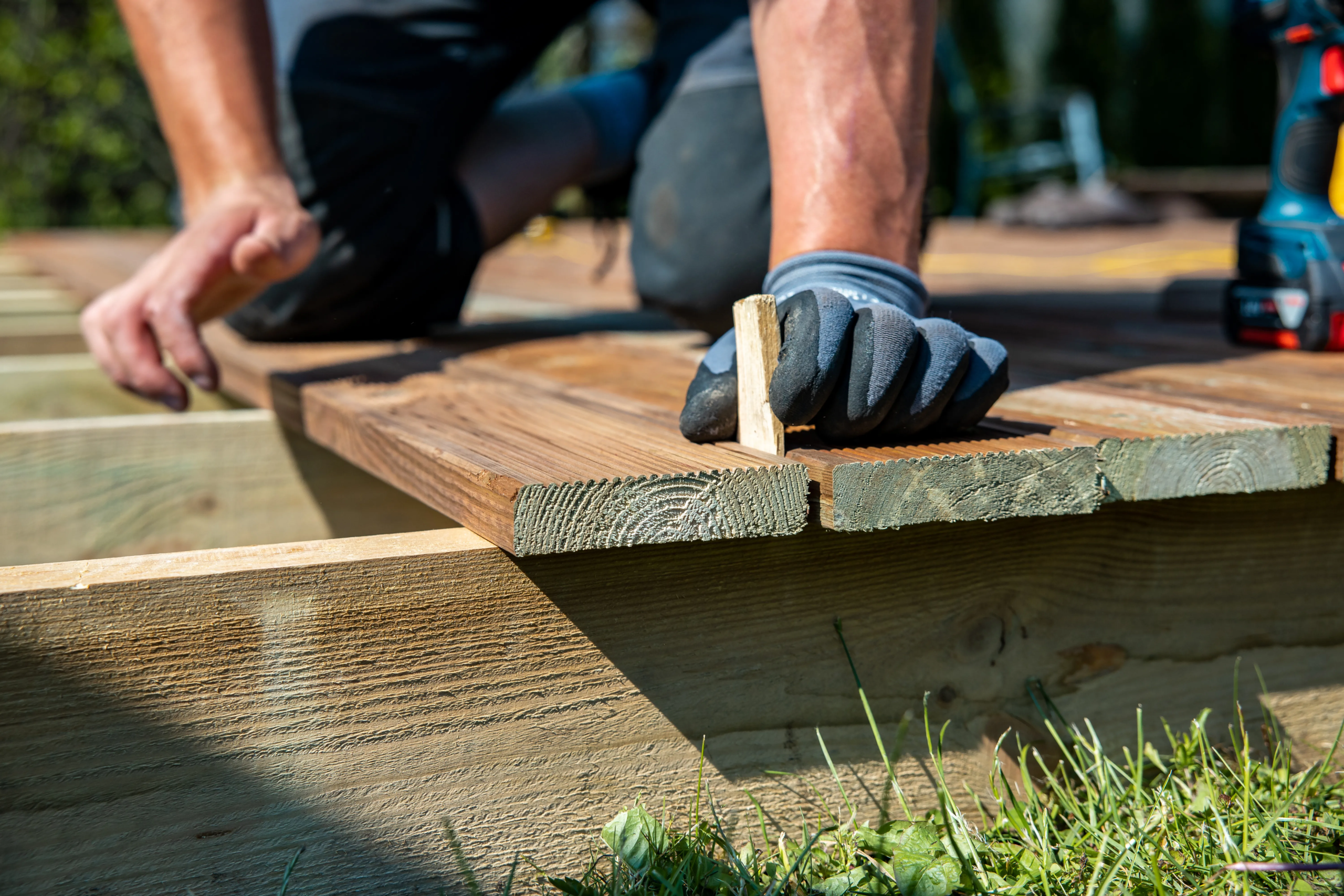 A contractor building a wooden deck in a backyard with natural wood materials