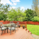 Custom-built wooden deck with a dining area and lounge chairs, enhancing a backyard’s aesthetic and functionality.